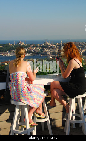 ISTANBUL, TURQUIE. Deux jeunes femmes de boire et donnant sur la ville à partir d'un bar sur le toit au quartier de Beyoglu. L'année 2009. Banque D'Images