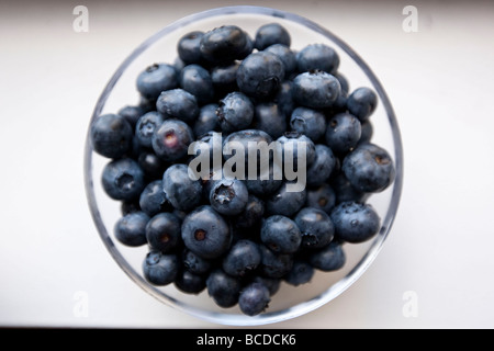 Poignée de bleuets dans un bol en verre sur un tableau blanc Banque D'Images