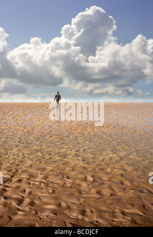 Un homme marche sur une plage pour un horizon lointain Banque D'Images