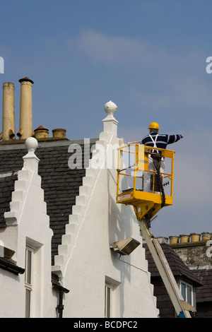 Peinture maison en utilisant 'grue' élévateur télescopique ou à Portree, Isle of Skye, Scotland, UK Banque D'Images