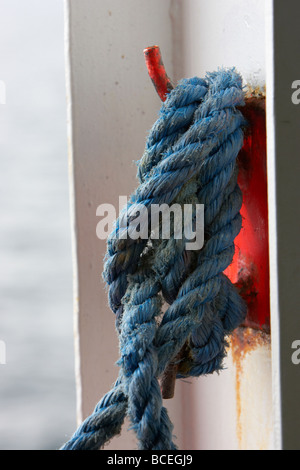 Blue corde nouée autour d'un bateau orange taquet sur le côté d'un navire en mer au Royaume-Uni Banque D'Images