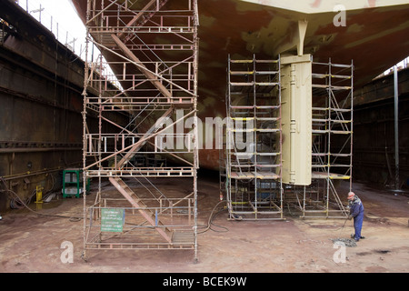 Travailleur de chantier naval sous grand navire à quai à Gdansk, Stocznia Remontowa. Banque D'Images