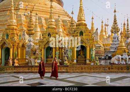 Le Myanmar, Birmanie, Yangon. Deux moines bouddhistes passer le petit stupas, temples et sanctuaires à la pagode Shwedagon Golden Temple Banque D'Images