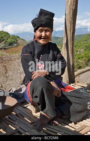Le Myanmar, Birmanie, Wan doi. Un Ann femme en costume traditionnel se trouve sur la plate-forme élevée de sa maison au village doi Wan. Banque D'Images