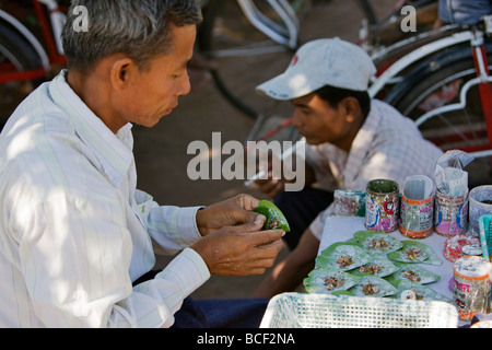 Le Myanmar, Birmanie, Yangon. Le propriétaire d'un petit écrou de blocage de la rue prépare ponderosa enveloppés dans des feuilles de bétel enduits à la chaux. Banque D'Images