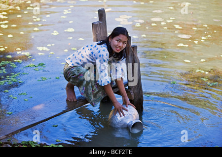 Le Myanmar, Birmanie, Mrauk U Une jeune femme Rakhine attire l'eau dans une casserole en aluminium à partir d'un étang d'eau de pluie près de son village. Banque D'Images