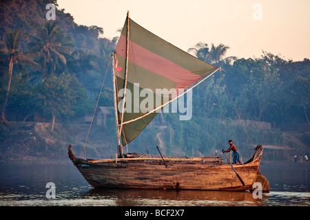 Un grand bateau en bois de conception de Rakhine sails le Lay Myo River dans fading lumière du soir. Banque D'Images