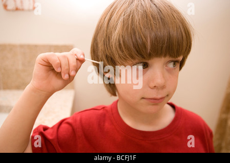 Sept ans son oreille de nettoyage avec un coton-tige Qtip Banque D'Images