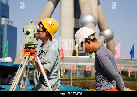 Surveyor et assistant avec son travail au théodolite par l'Oriental Pearl District de Pudong à Shanghai en Chine. Banque D'Images