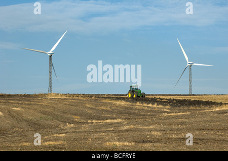 Un agriculteur laboure avec son tracteur près de deux éoliennes Alberona Italie Banque D'Images