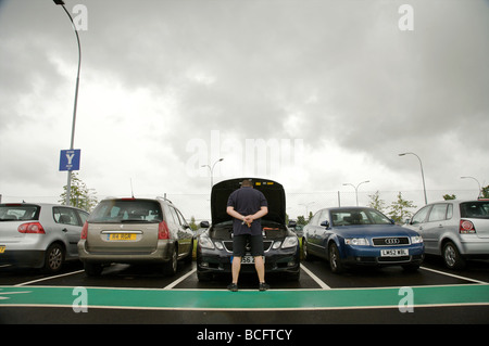 Voiture en panne dans un parking de l'aéroport avec le propriétaire Banque D'Images