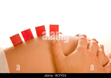 Jouet en bois rouge quatre blocs sur une pregnant belly Banque D'Images