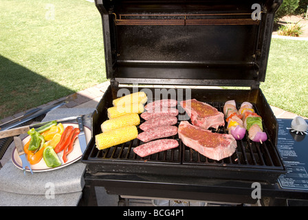 Un barbecue prêt à cuire des épis de maïs steak brochettes de poulet et saucisse Banque D'Images