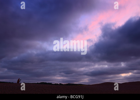 Un photographe solitaire sur une banque de galets à Claj capturant le coucher du soleil sur la côte nord du comté de Norfolk Banque D'Images