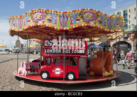 Rond-point de childrens carousel ride sur la promenade du bord de mer présentent un mini London Bus Tour sit-on réplique à Brighton. Banque D'Images