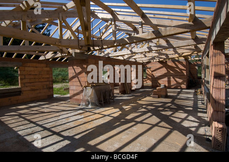 Ombres de fermes de toit et des poutres en criss cross le plancher et les murs d'une maison en construction Banque D'Images