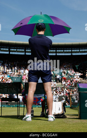 Ballboy holding umbrella comme parasol sur le Court Central au Wimbledon Championships Banque D'Images