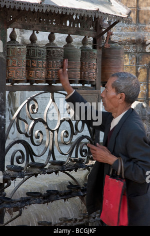 Katmandou, Népal. Filature roues de prière à l'homme de culte, Temple de Swayambhunath. Banque D'Images