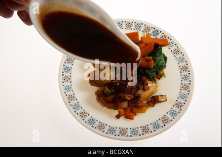 Dîner de poulet sur la plaque avec de la sauce étant versé sur Banque D'Images