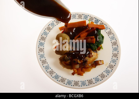 Dîner de poulet sur la plaque avec de la sauce étant versé sur Banque D'Images