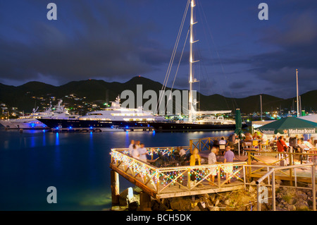 Un restaurant au bord de l'eau bénéficie d'une vue sur de grands yachts dans le port de Saint Martin, Caraïbes. Banque D'Images