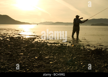 Pêche à la mouche l'homme rive de la baie Sitka SE AK de l'été près de Harbour Pt Silhouette Banque D'Images