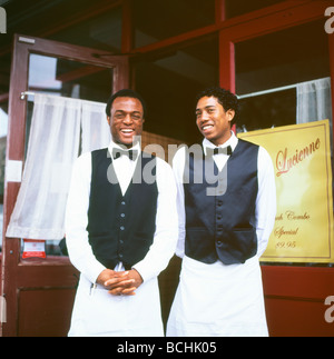 Deux serveurs noirs en tabliers et nœuds papillon saluent les clients souriants à l'extérieur du restaurant chez Lucienne Harlem New York City, NY KATHY DEWITT Banque D'Images