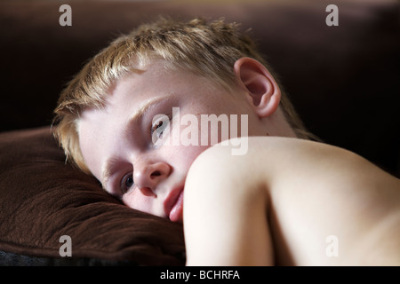 Triste et seul à la maison jeune garçon portant sur un canapé Banque D'Images