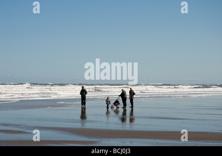 Une famille braver les conditions météorologiques sur une Britsh source chaude journée sur la plage à Whitby, dans le Yorkshire du Nord. Banque D'Images