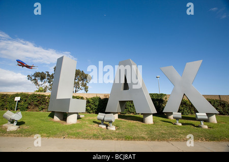 Trois lettres dimensionnelles à LAX (l'Aéroport International de Los Angeles) avec jet dans le ciel en arrière-plan. La Californie. Banque D'Images