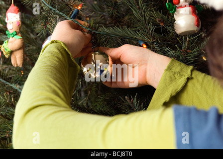 Close up of a woman's hands en un ornement sur un arbre de Noël Banque D'Images