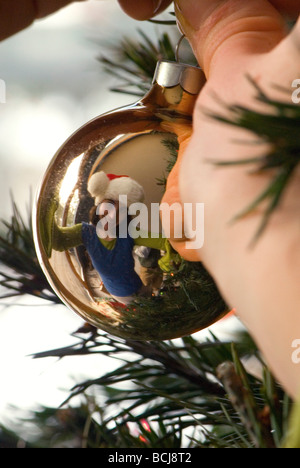 Close up of a woman's hands en un ornement sur un arbre de Noël Banque D'Images