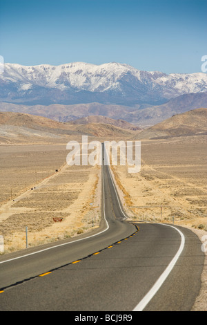 Nevada l'autoroute 50, route droite dans désert, route est connu comme 'plus solitaire dans l'autoroute du Nord' des montagnes enneigées au loin. Banque D'Images