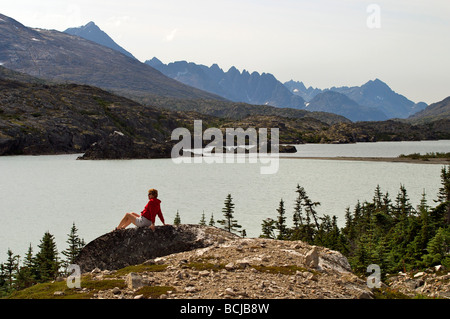 Female hiker bénéficie d'une vue sur le lac au Klondike Gold Rush National Historic Park au nord de Skagway, Alaska Banque D'Images