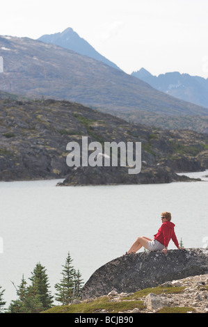 Female hiker bénéficie d'une vue sur le lac au Klondike Gold Rush National Historic Park au nord de Skagway, Alaska Banque D'Images