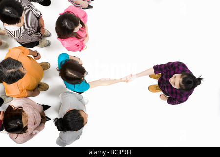 Woman shaking hands avec quelqu'un dans la foule Banque D'Images