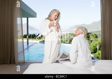 Couple d'âge moyen portant des salles de bains dans la chambre avec vue sur la piscine Banque D'Images