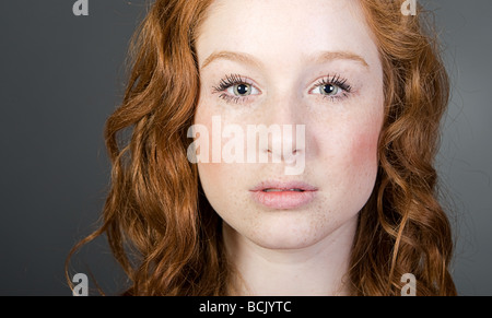 Studio Shot d'un adolescent à la tête rouge contre Gray Banque D'Images