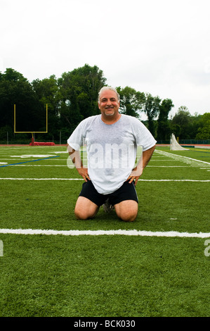 L'excès de l'âge moyen à la retraite et senior man stretching les muscles des jambes après s'exercer sur un terrain de sport en plein air Banque D'Images