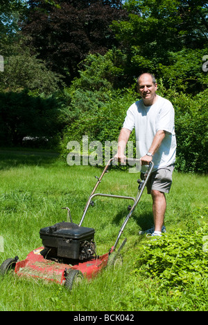 Beau moyen age homme envahi par la coupe de l'herbe avec tondeuse à suburban house Banque D'Images