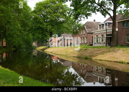 Les bâtiments en brique rouge typique des Pays-Bas jetaient un reflet dans l'eau immobile d'un canal avec des arbres Banque D'Images