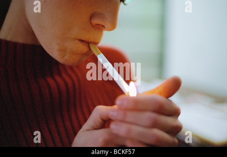 Jeune femme cigarette d'éclairage Banque D'Images