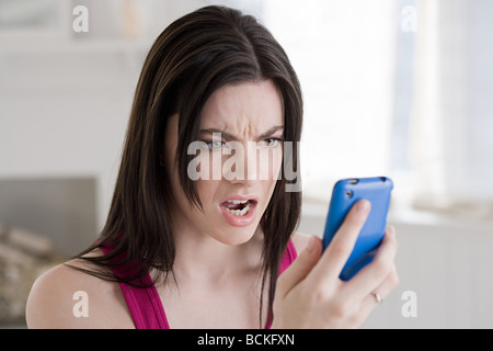 Angry woman looking at cellphone Banque D'Images