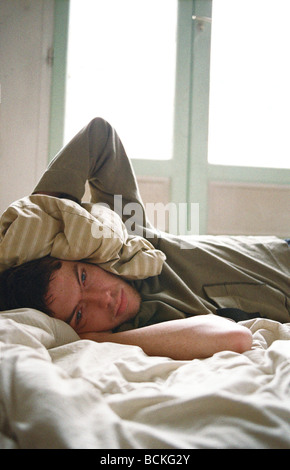 Young man lying on bed Banque D'Images