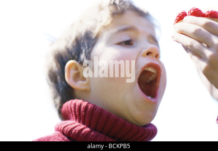 Enfant avec bouche ouverte pour prendre bouchée de dessert Banque D'Images