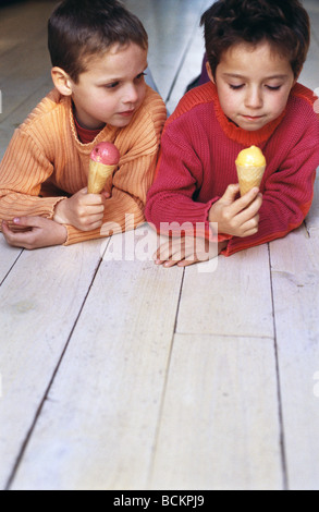 Deux enfants allongés sur plat ventre sur le marbre manger icecream cones Banque D'Images