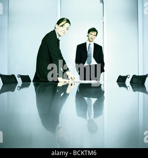 Businessman and businesswoman standing at table Banque D'Images