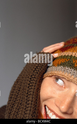 Young woman wearing hat avec la main sur le côté de la face, smiling, close-up Banque D'Images