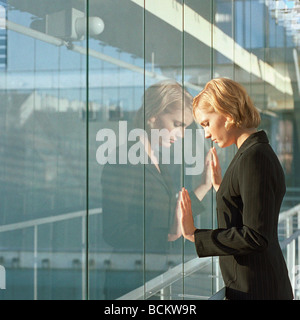 Jeune femme avec des mains pressées contre fenêtre, side view Banque D'Images