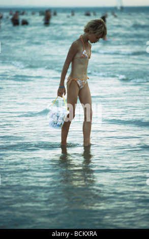 Girl holding godet, walking in surf